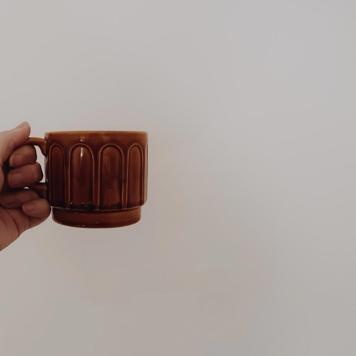 a hand holding a brown cup of tea