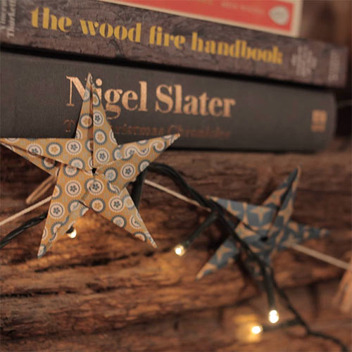 fairy light and star garland in front of a pile of books