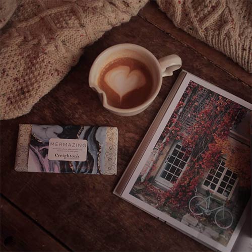 cup of coffee, a magazine and knitwear on a table