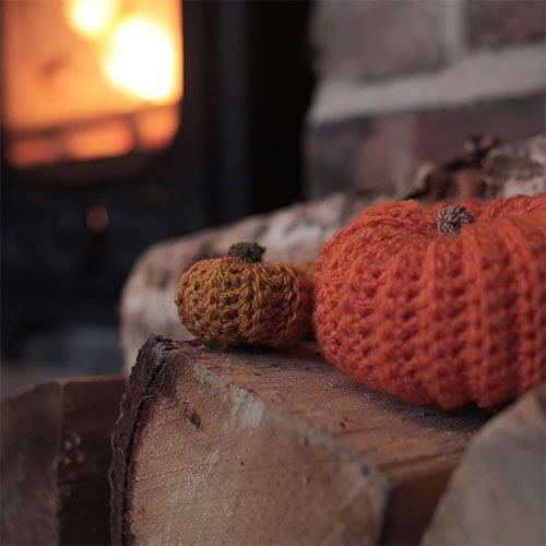 knitted pumpkins in front of a wood fire