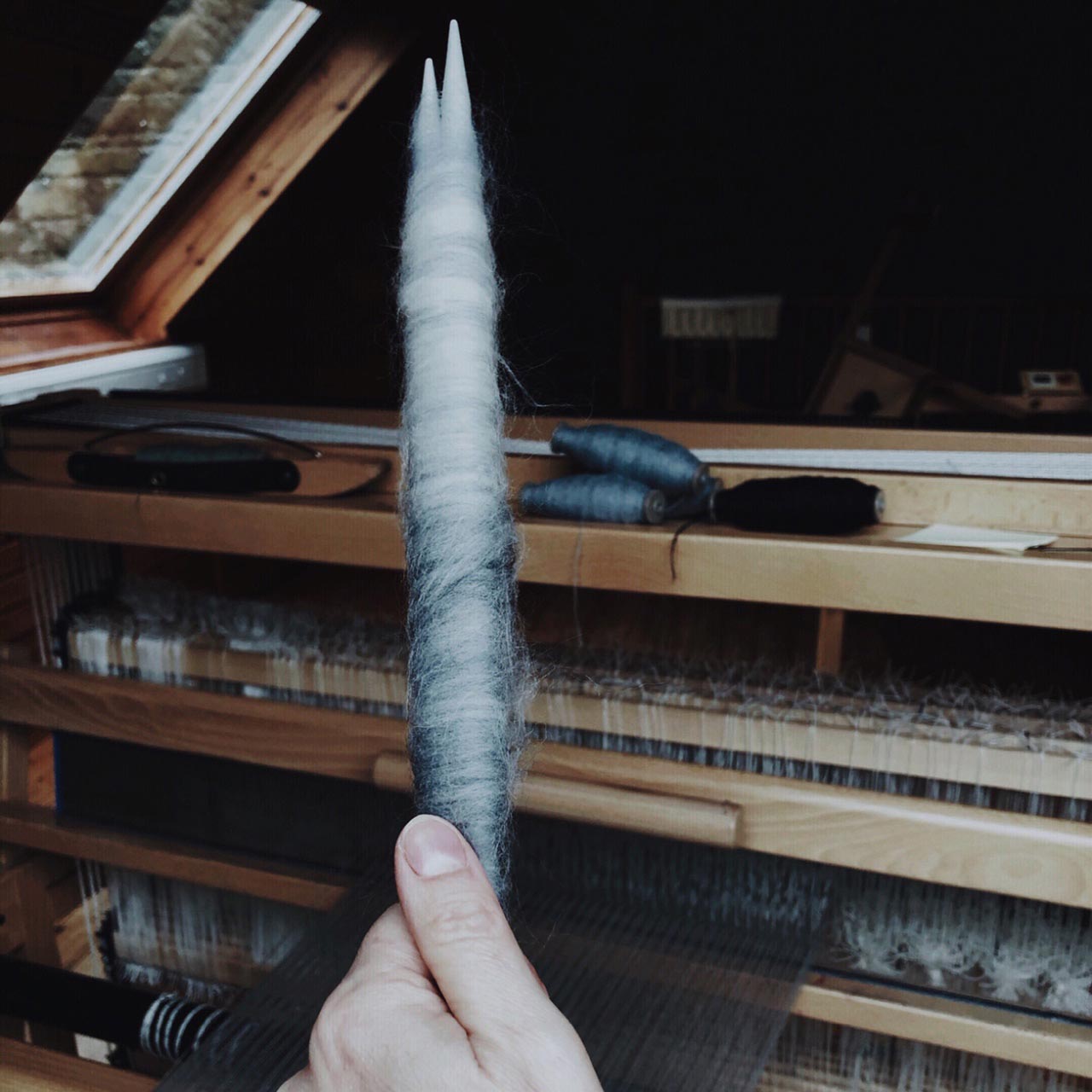 a hand holding yarn for a loom