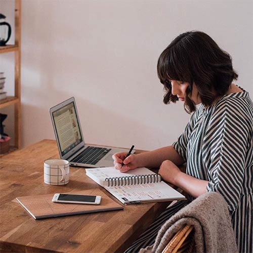 jen carrington sitting at a table working on her laptop