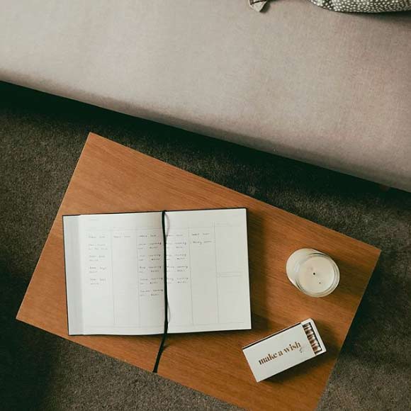 a journal, candles and matches on a brown table next to a couch