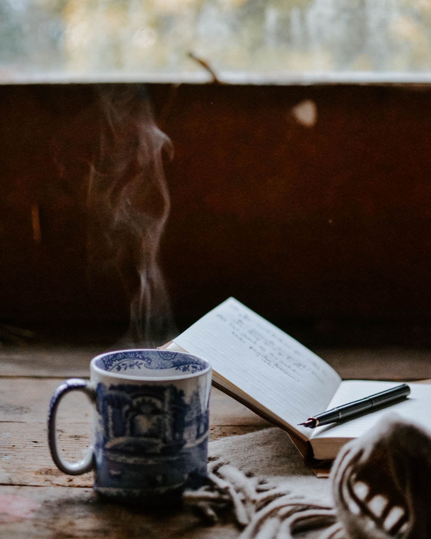 a steaming cup of tea with a notebook and pen