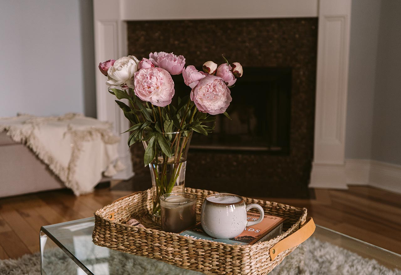 a table with a vase with flowers, a tray with a cup of coffee, a fireplace in the background