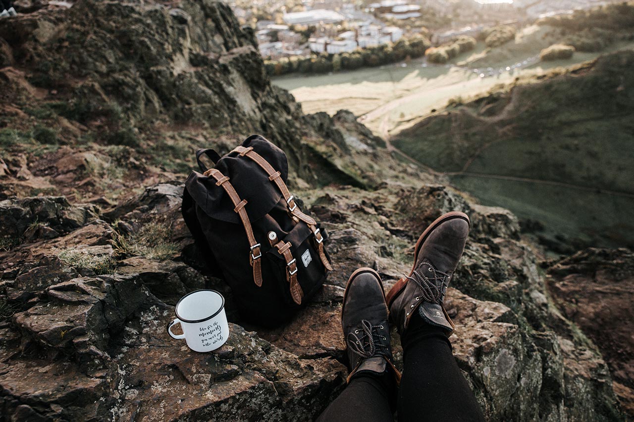 a backpacker resting in the hills with a cup of tea