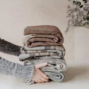 two hands holding a pile of scarves from The Tartan Blanket Company