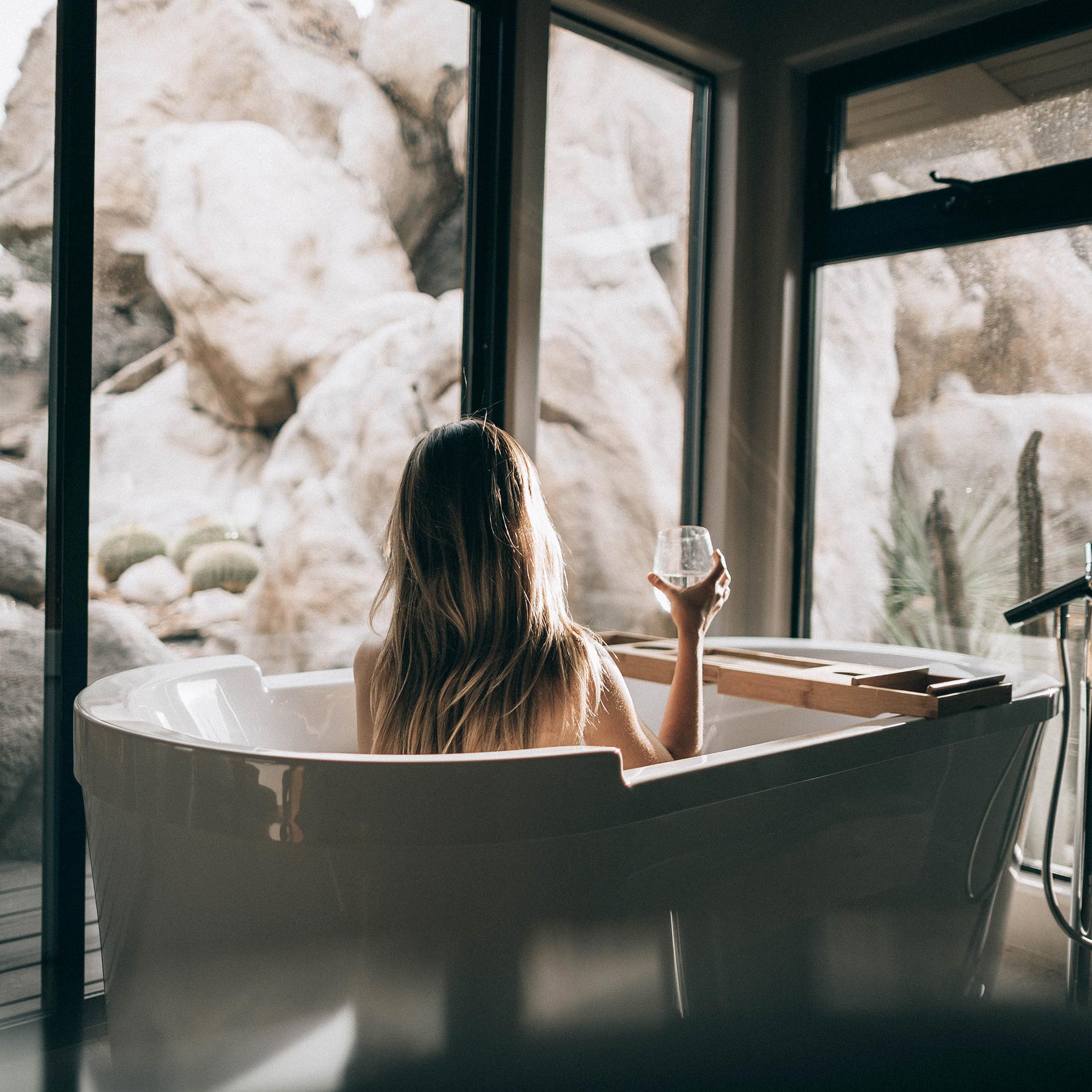 woman taking a bath holding a glass of water - self-care