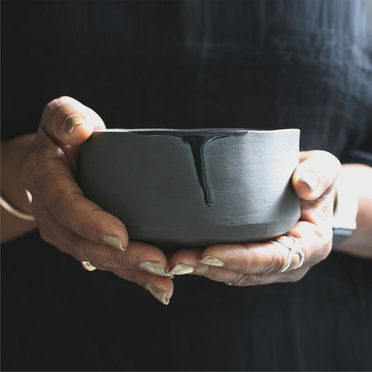 two hands holding a blue ceramic bowl from naked clay ceramics