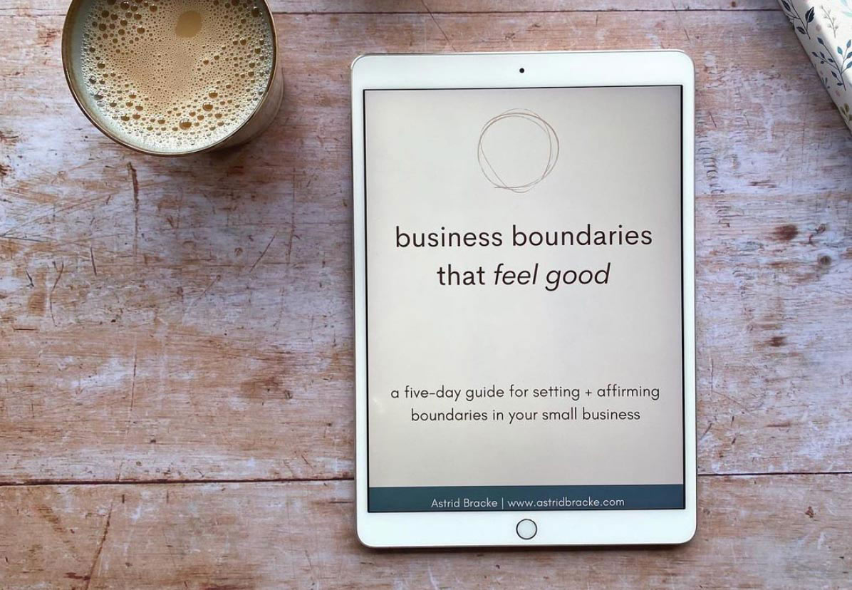 flatlay with tablet with ebook 'business boundaries that feel good' by Astrid Bracke and cup of coffee on a wooden table