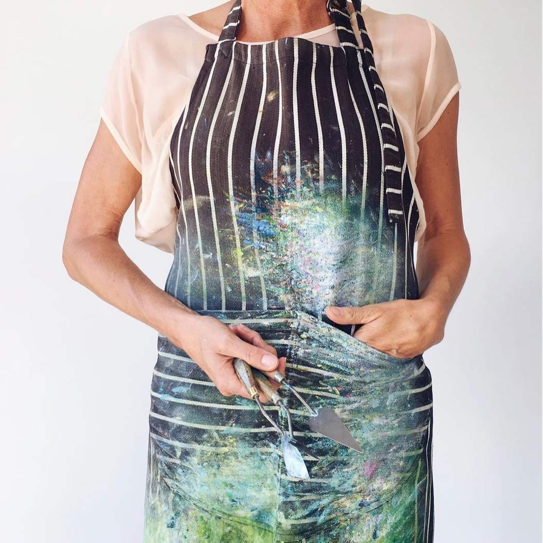 torso of Sue Rapley dressed in a painter's apron and holding painting tools