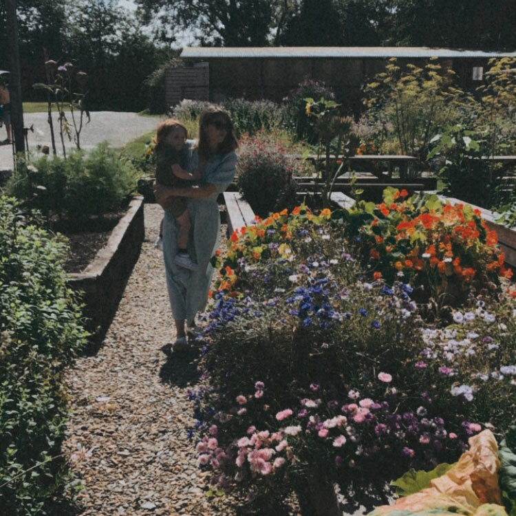 Amy Bateman holding a child in her garden - holistic living