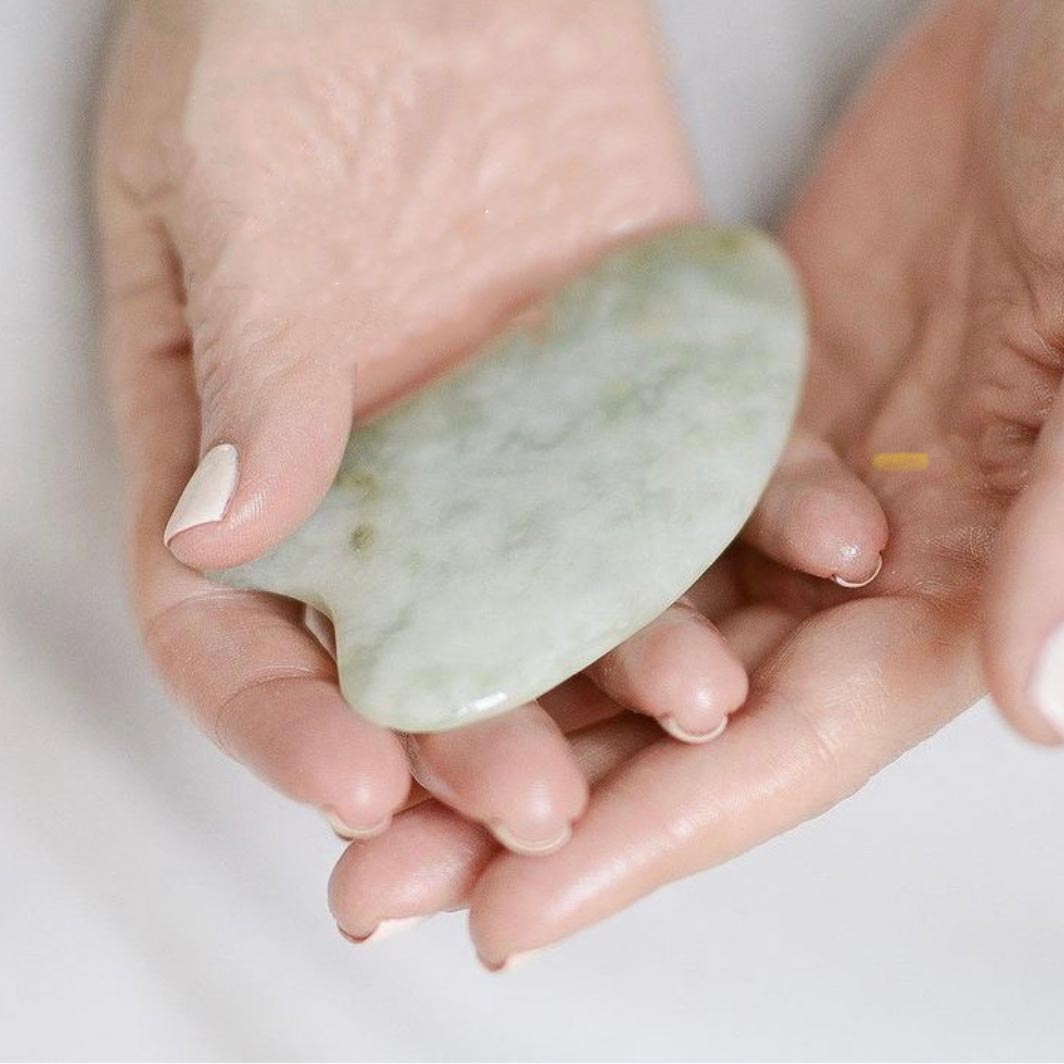 two woman's hands washing hands with a rock - holistic living - qua she