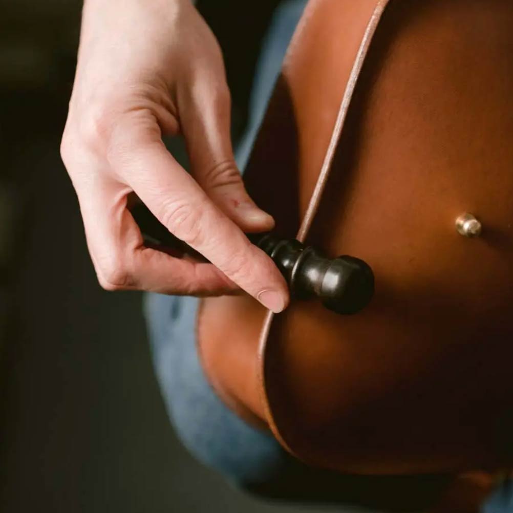 hand of leather worker paula kirkwood finishing the edges of a leather bag