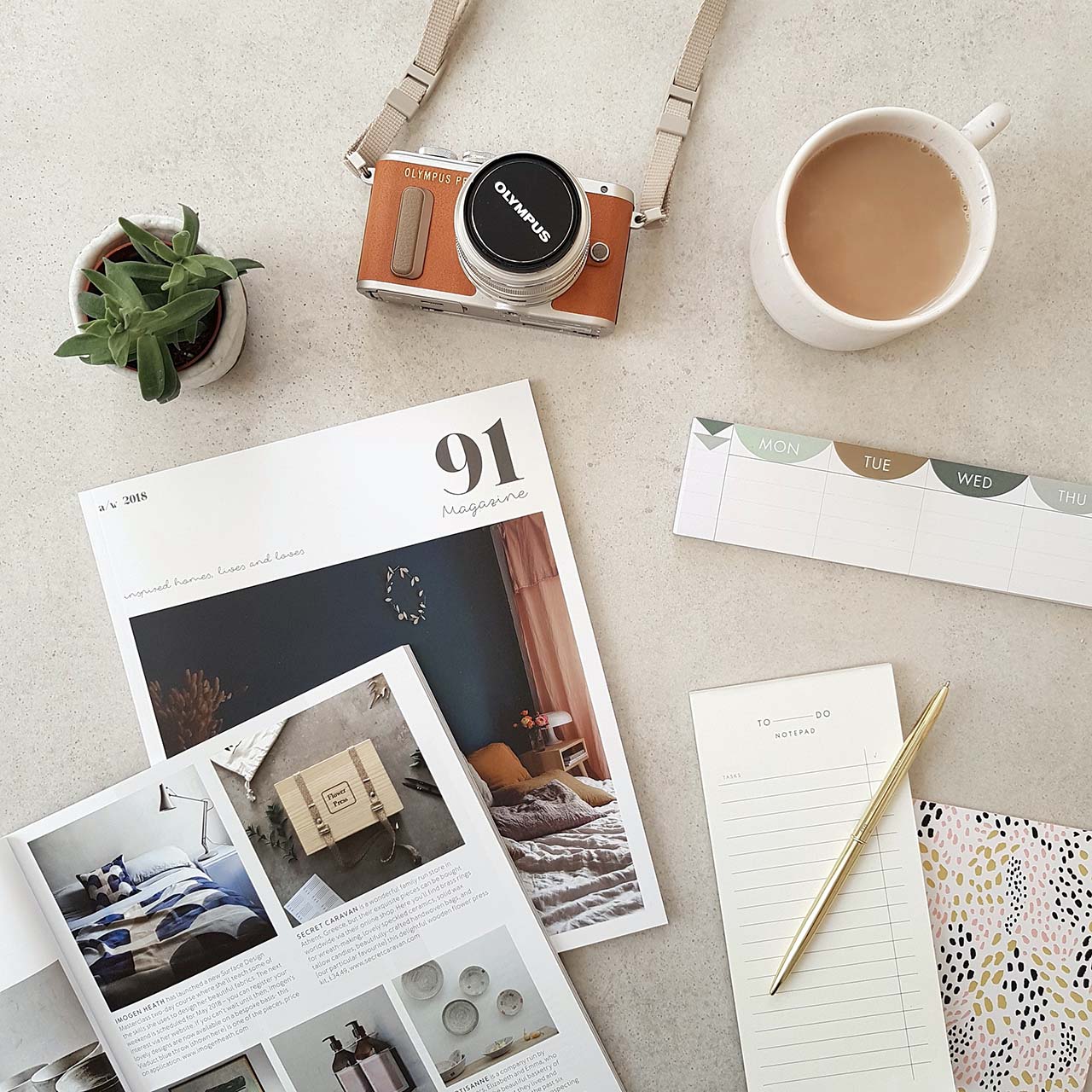 a copy of 91 magazine seen from above surrounded by a cup of coffee, a plant, a camera, a notebook and pen - inspiration for slow and seasonal living