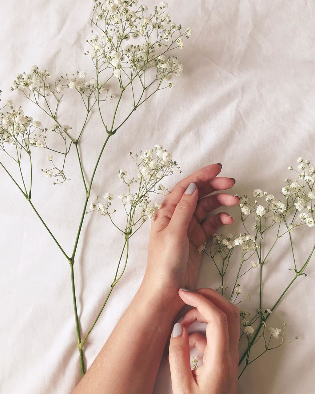 two woman's hands on a white sheet with stems of gypsophila - balance between work and play