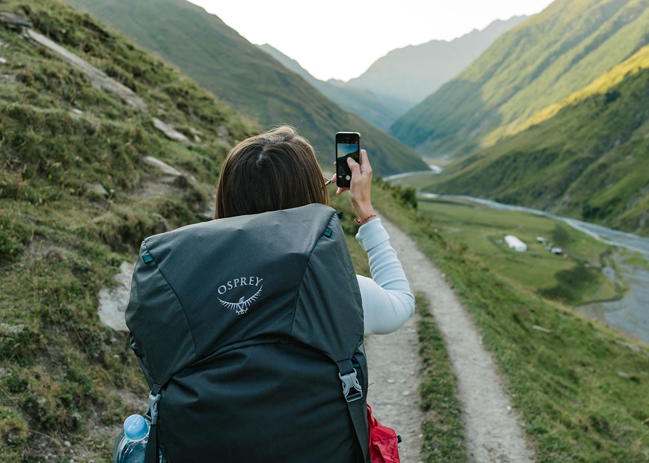 woman with a backpack walking through nature - why slow travel is the perfect way to enjoy summer