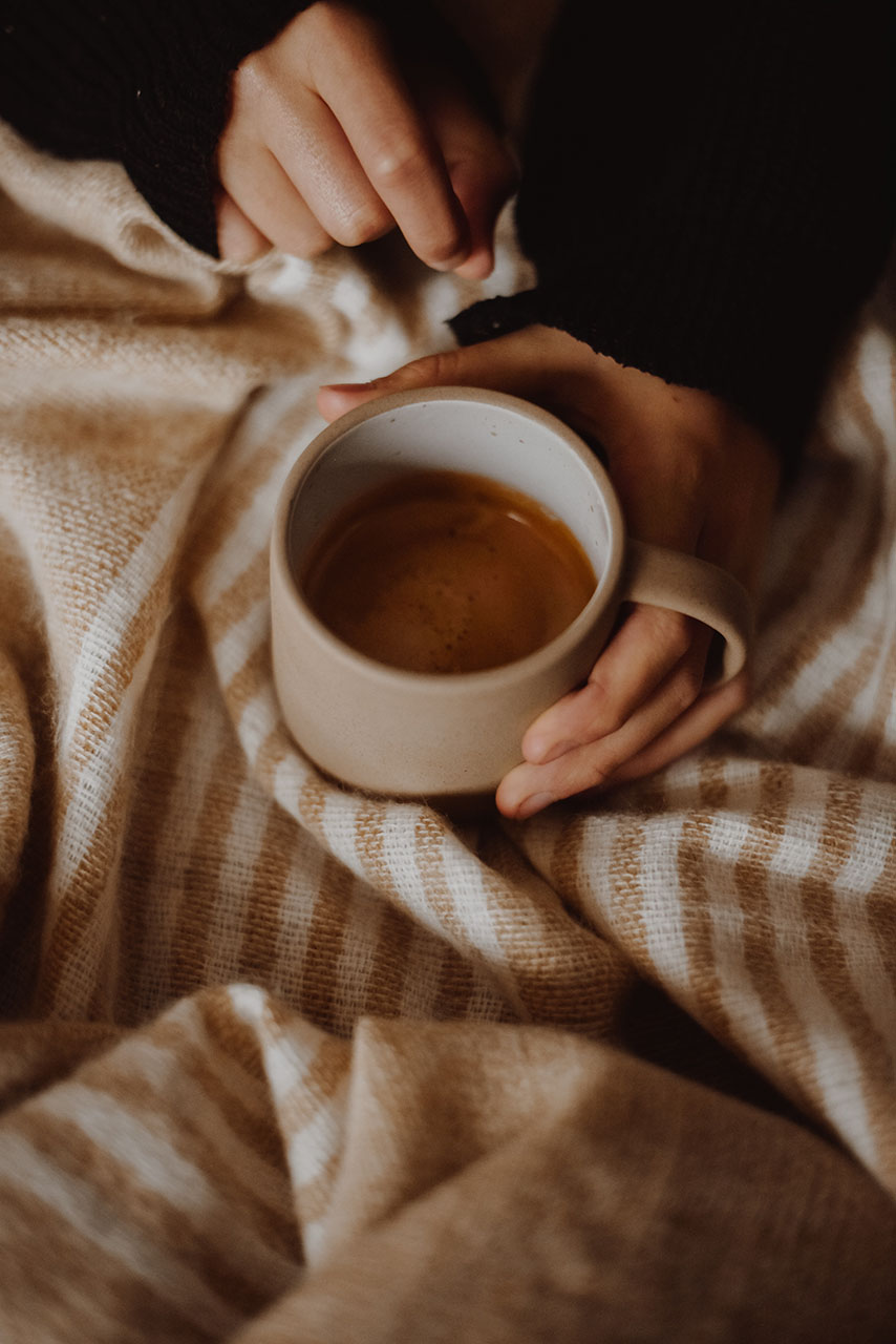 a woman holding a ceramic mug with a hot drink