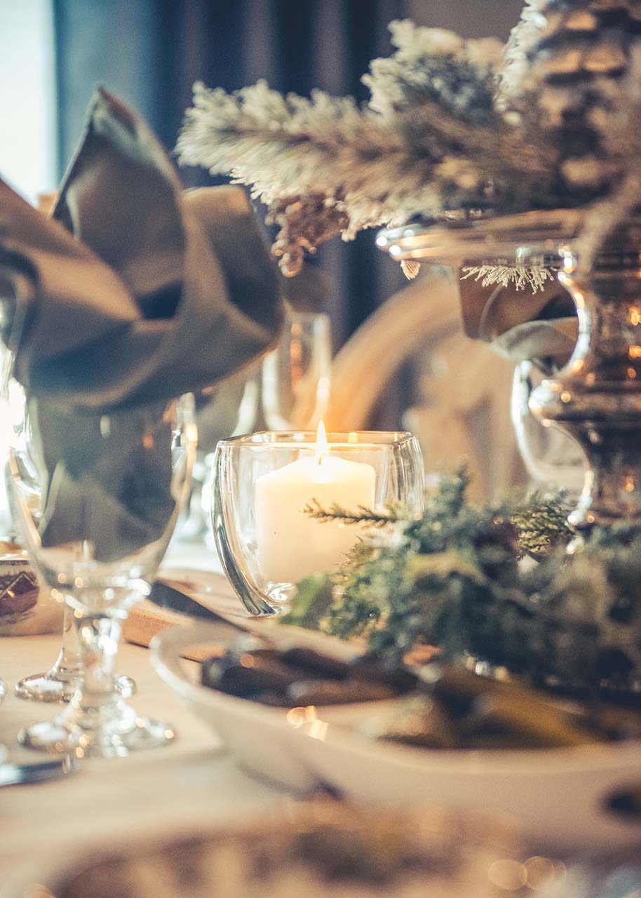 a Christmas table decorated with candle, foliage, sustainable linens