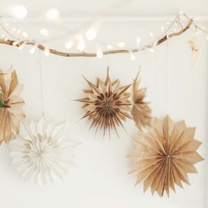 multiple brown and white paper stars hanging on a branch with fairy lights