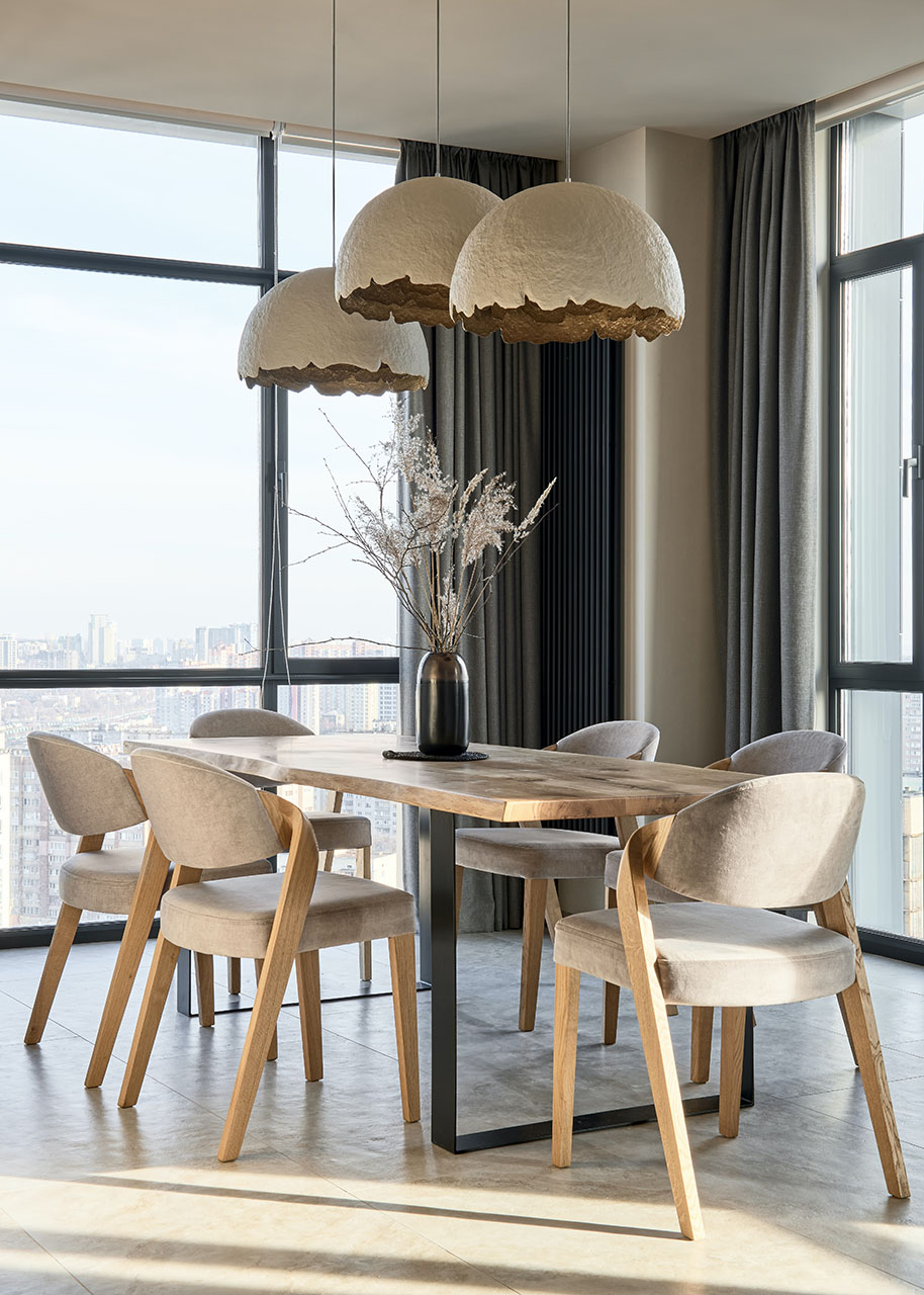 a dinner table with chairs and big decorative lamps above it