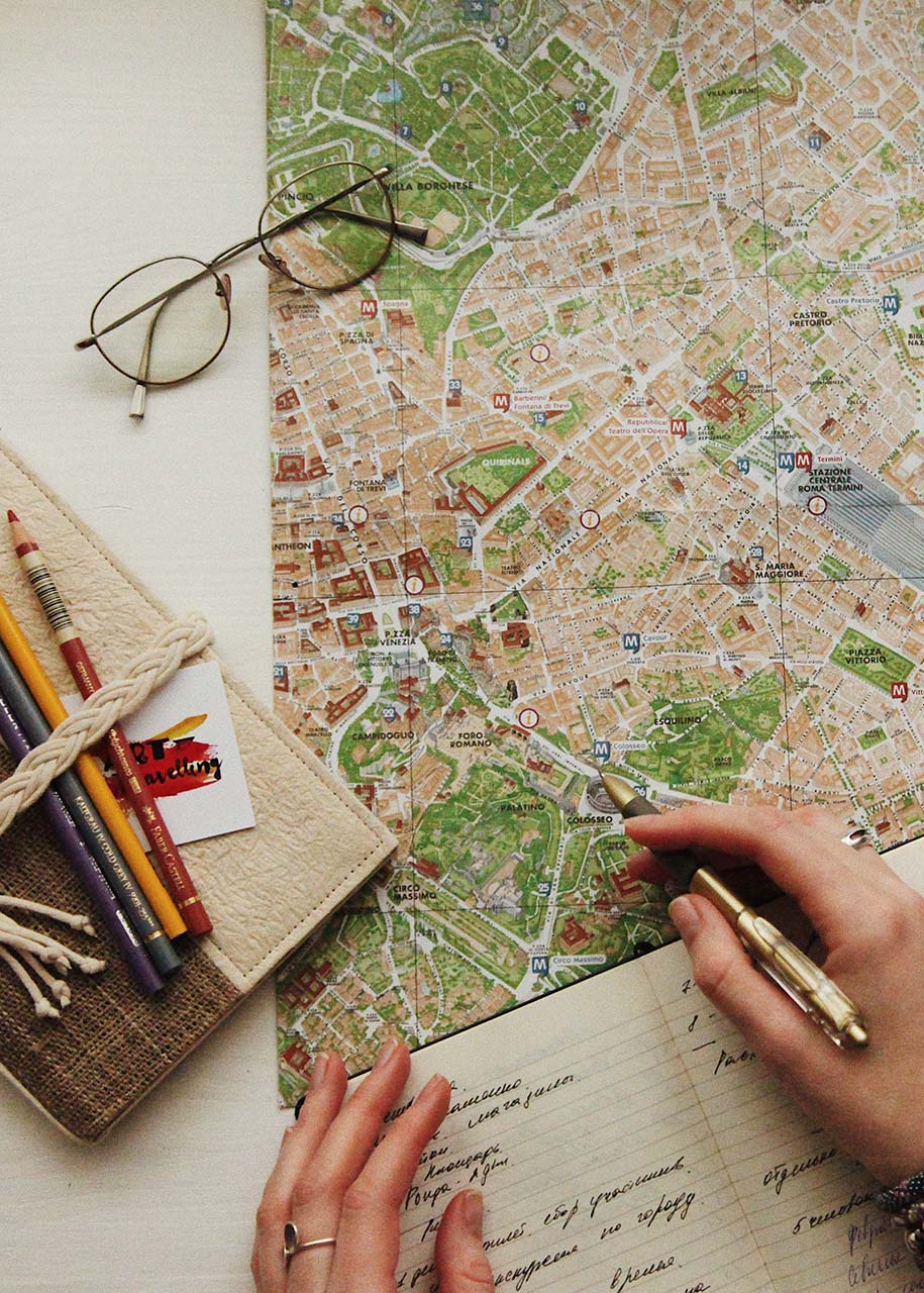 a woman planning a vacation trip using a city map, a notebook and pens