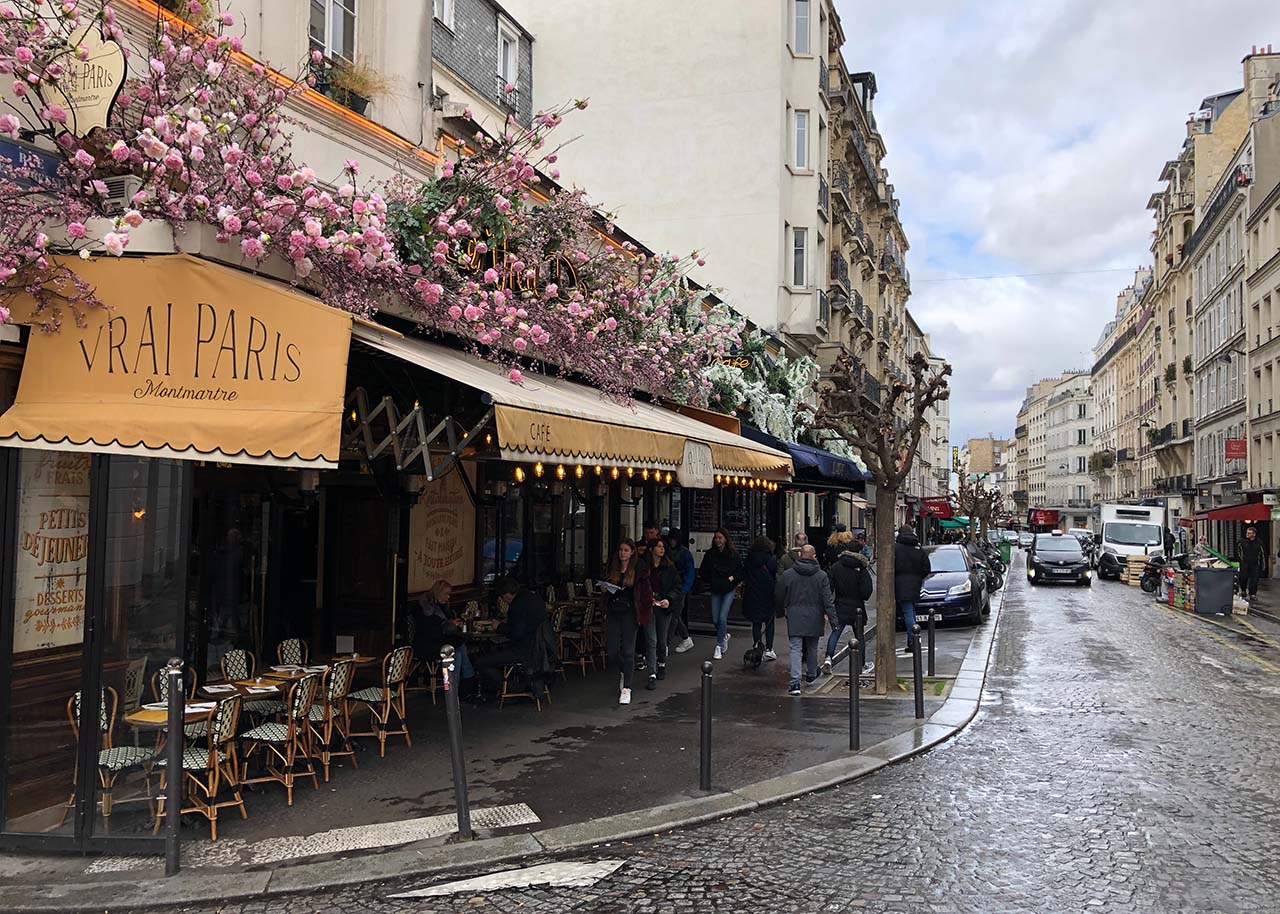 a cafe on a busy street in Paris in spring time - ways to slow down on your city trip
