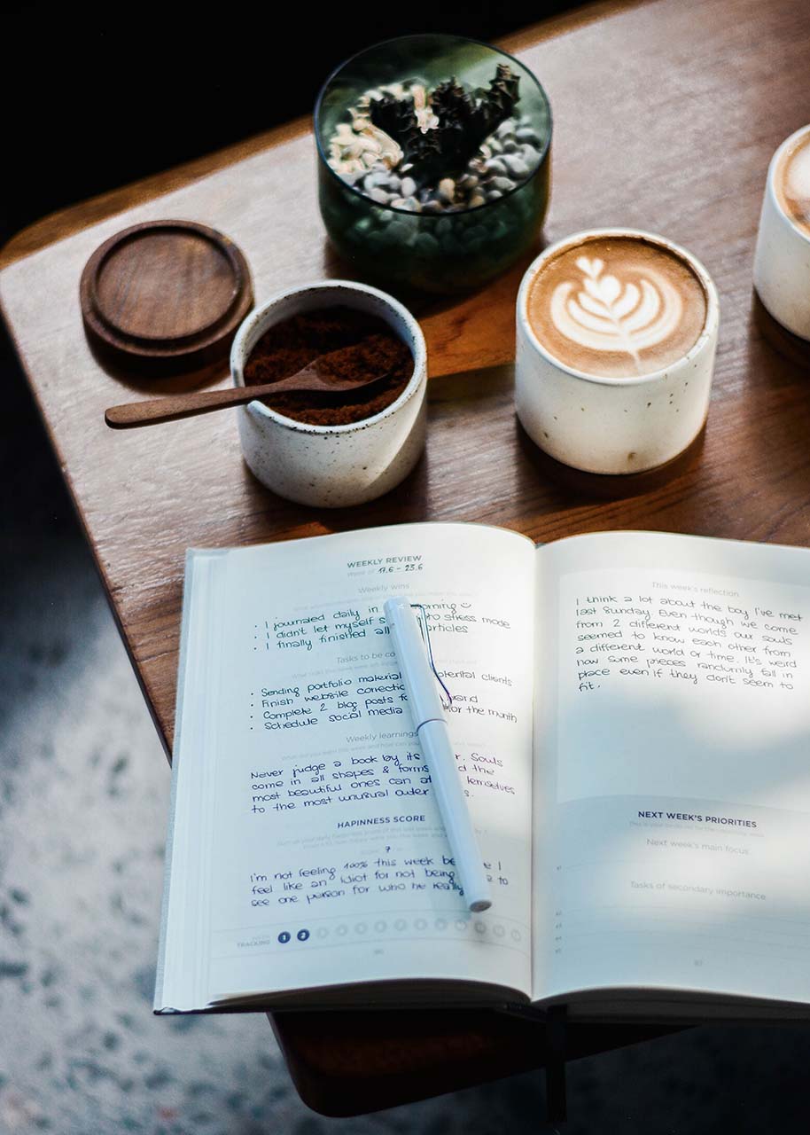 an open gratitude journal on a wooden table with a cup of coffee and a succulent plant on the side