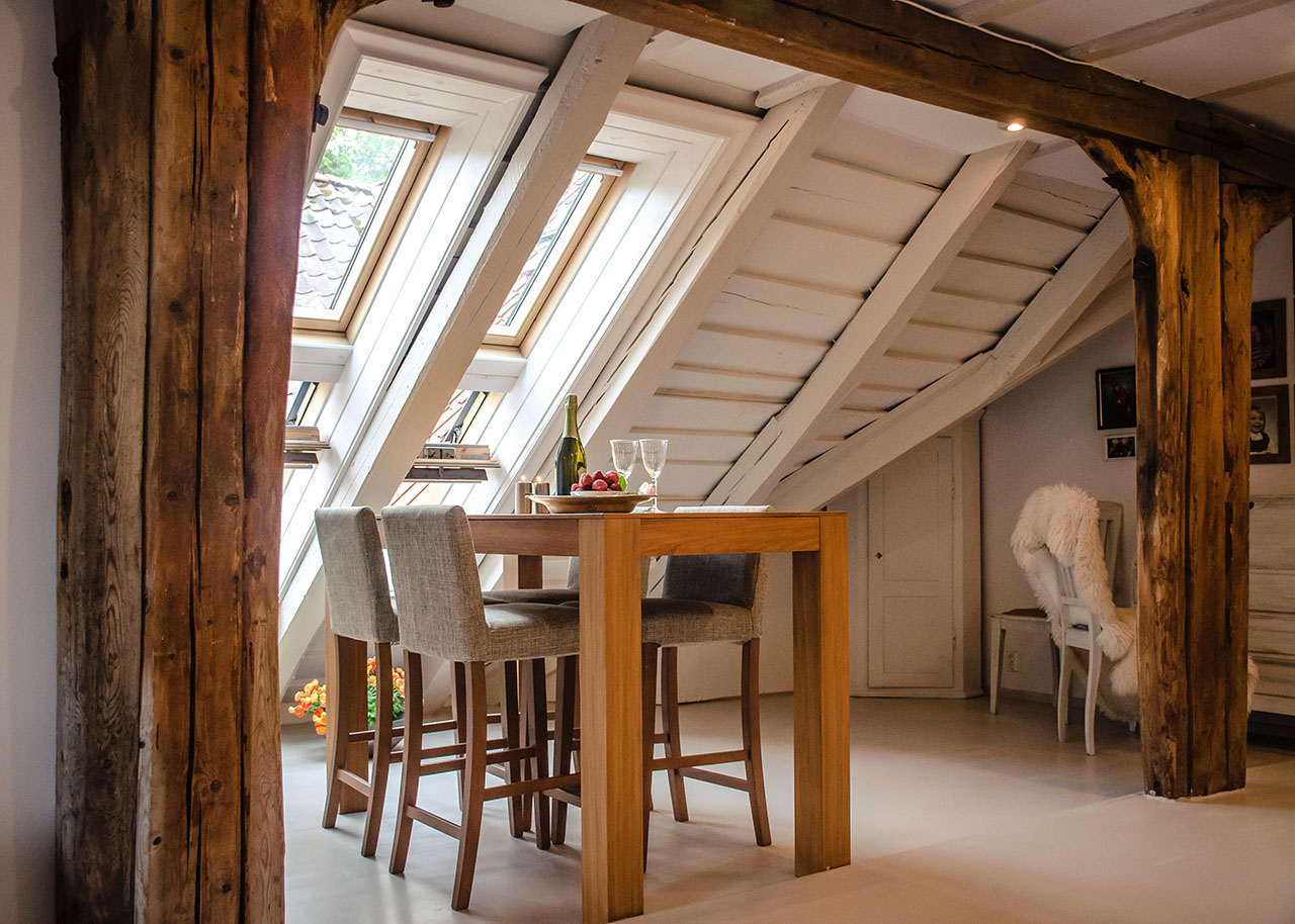 a cosy table and chairs next to windows in the roof