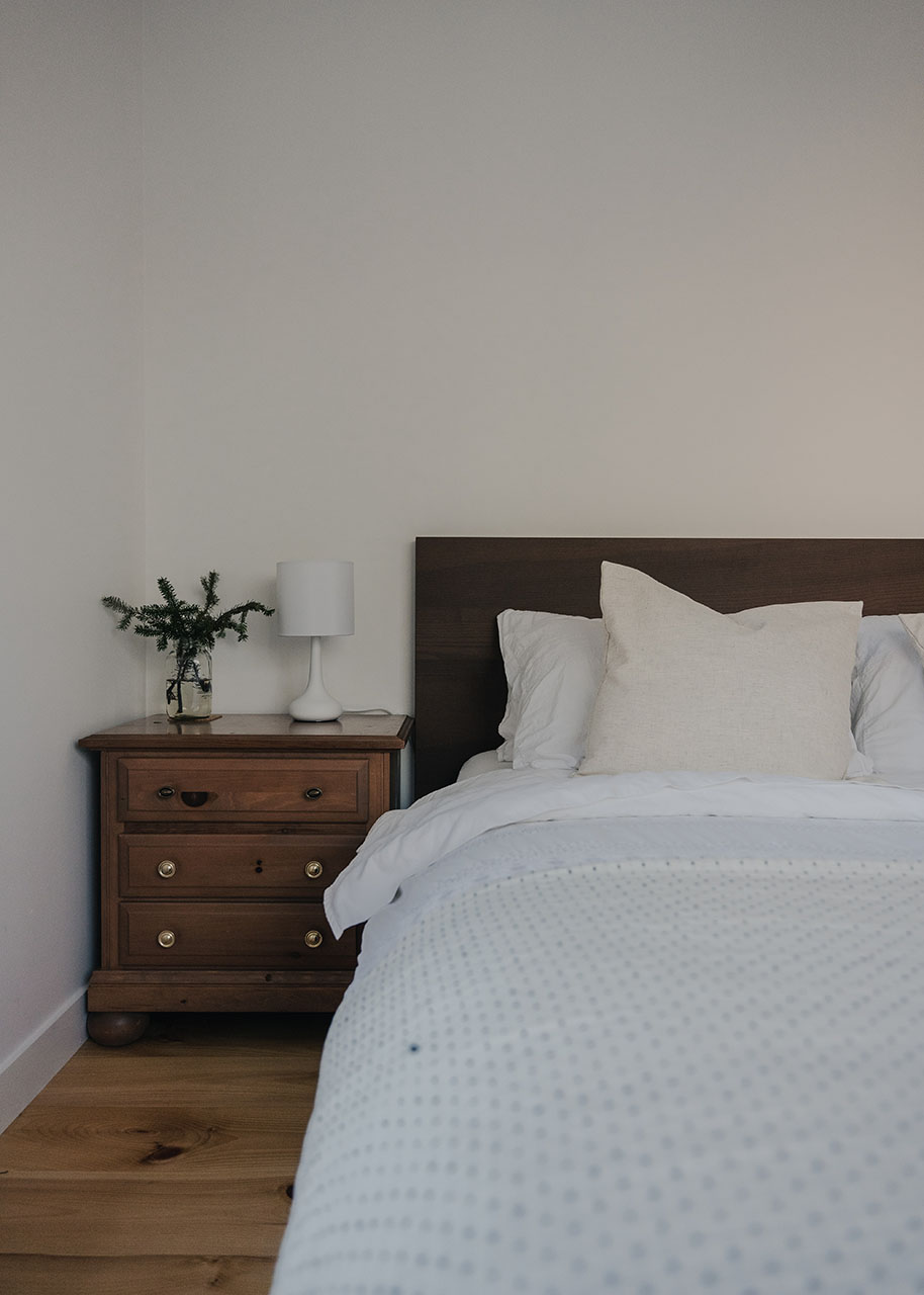 wooden bed and side table with white linen, white walls and wooden floor - eco-friendly furniture