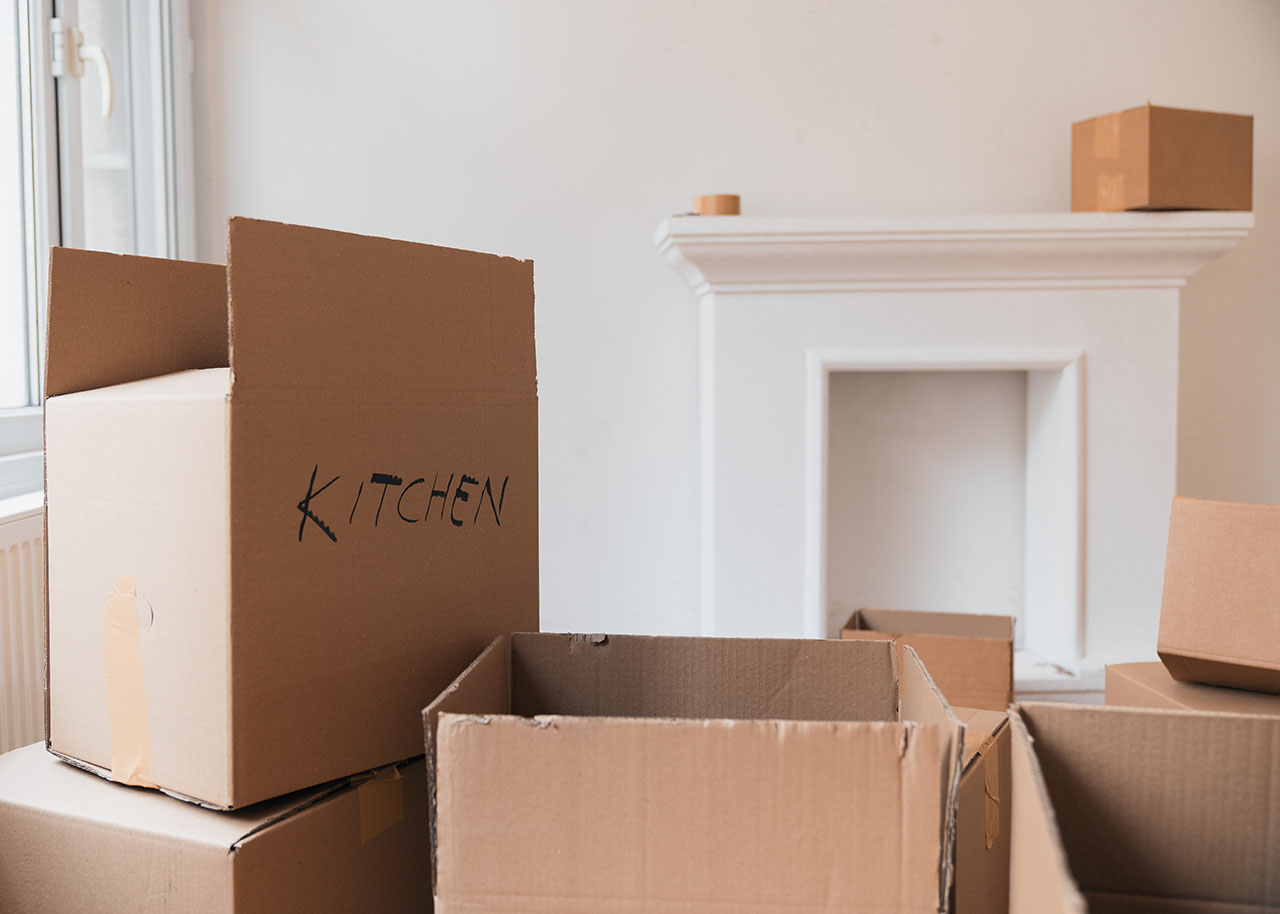 a pile of moving boxes in an empty living room - How to make your house move less stressful