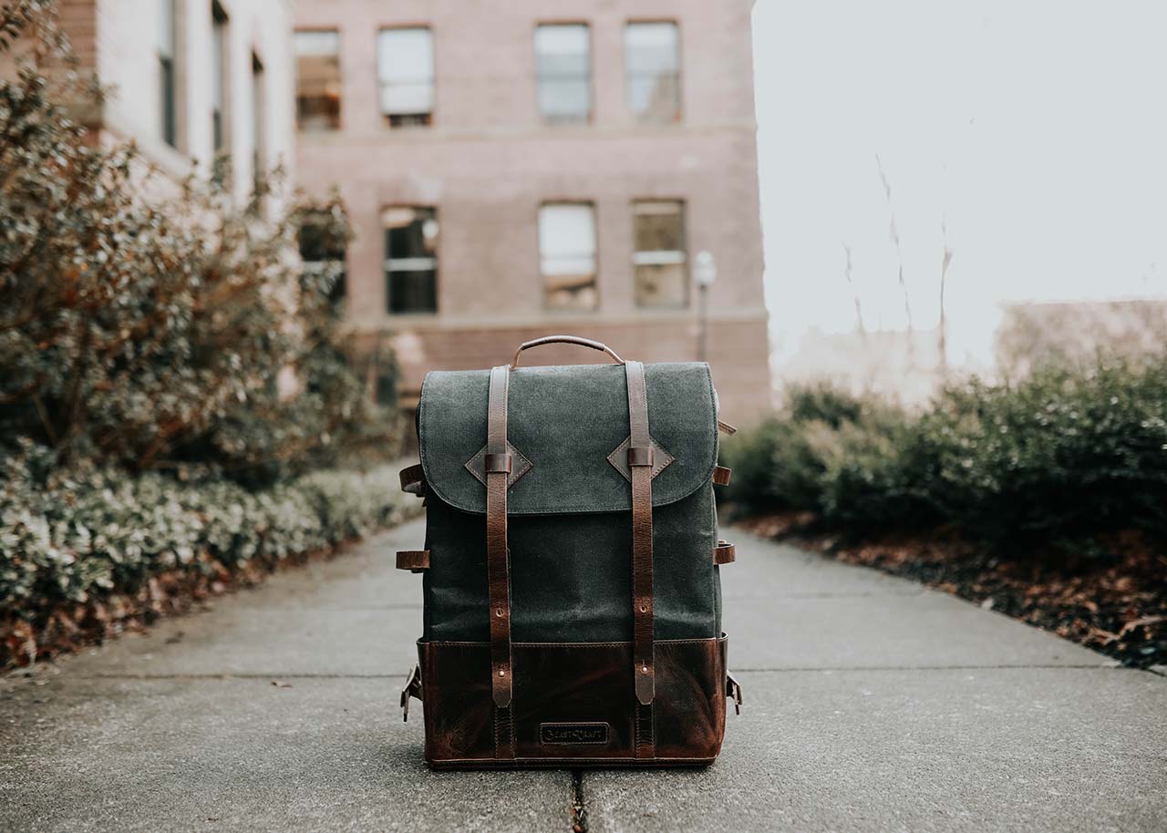 a backpack standing on the pavement in front of a building - the slow living guide blog category travel & explore