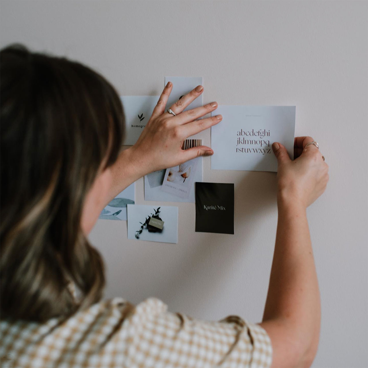woman creating a branding moodboard on a wall - slow design
