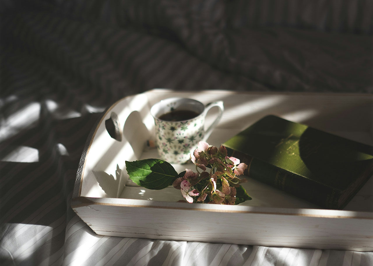 a white wooden tray with a cup of tea, a hydrangea flower and a book - slow living 101