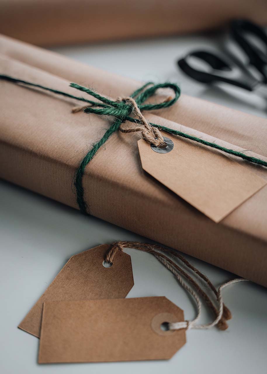 a gift wrapped in craft paper and rope bows with paper labels - sustainable gift wrapping