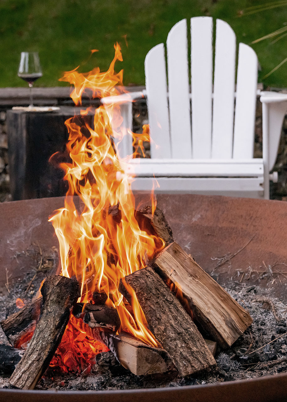 a fire burning in a fire pit with a white lounge chair in the background