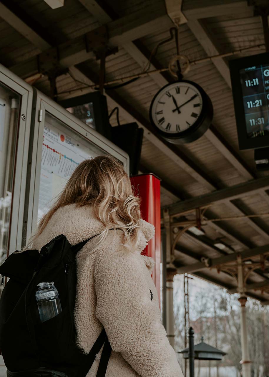 a woman with a backpack at a train station - slow travel by train