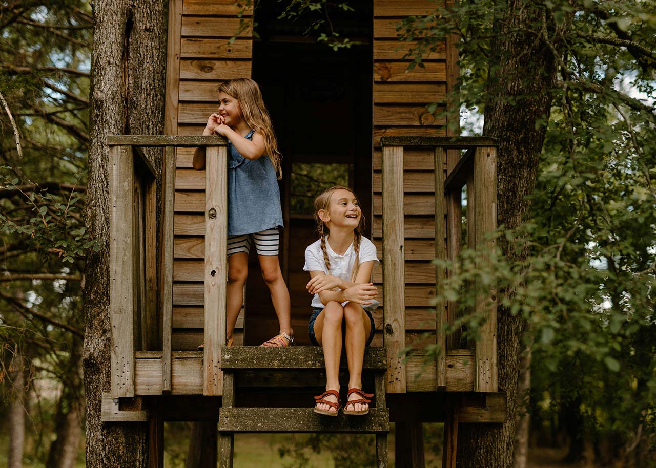 two girls sitting in a tree house having outdoor fun