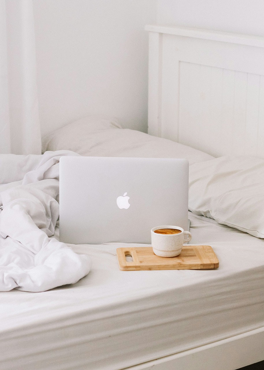 a laptop and a cup of tea on an unmade bed - Mindful financial practices for small business owners