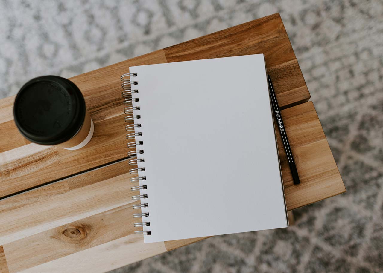 a side table with a blanc notebook and a cup of coffee - starting a small business