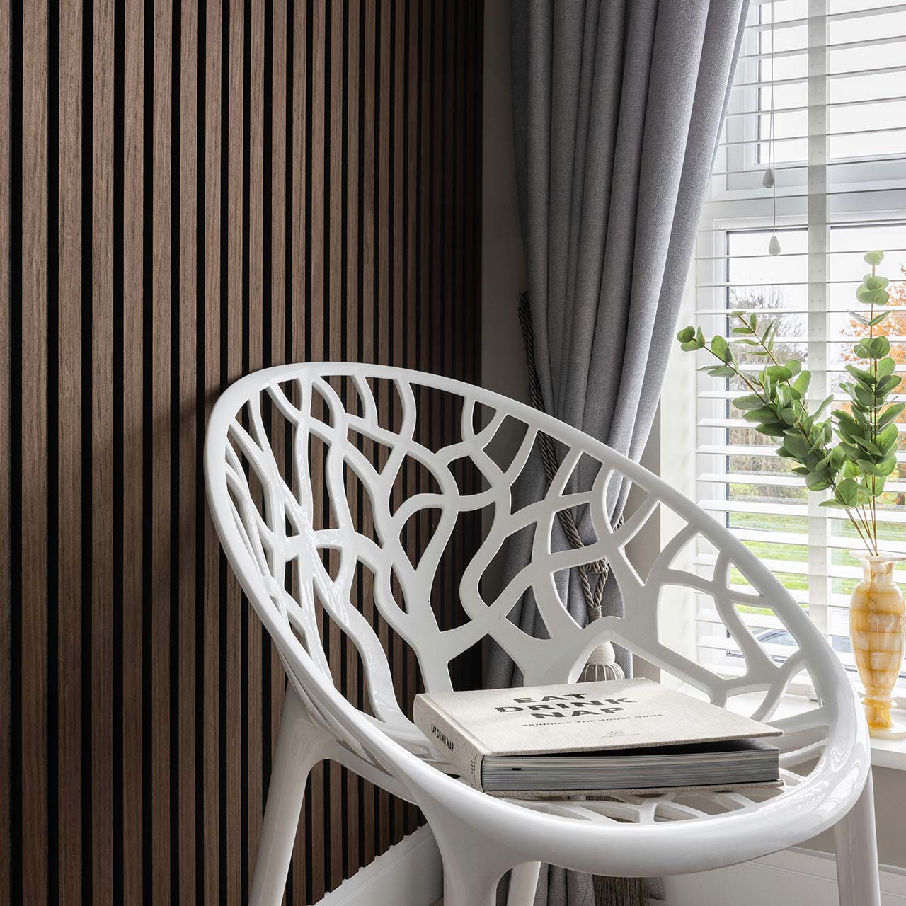 a white chair in front of a wood panelled wall - ideas to liven up a bare wall