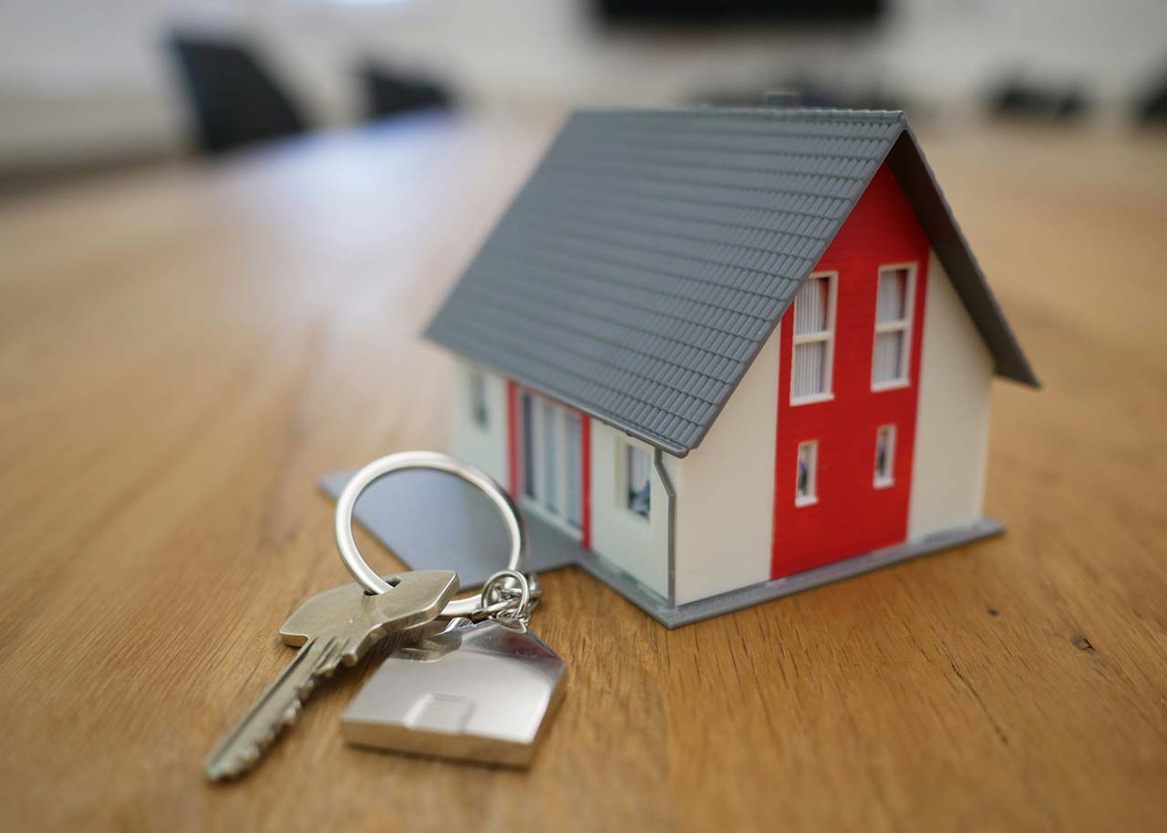 a house miniature and a set of house keys with a keychain - selling your home