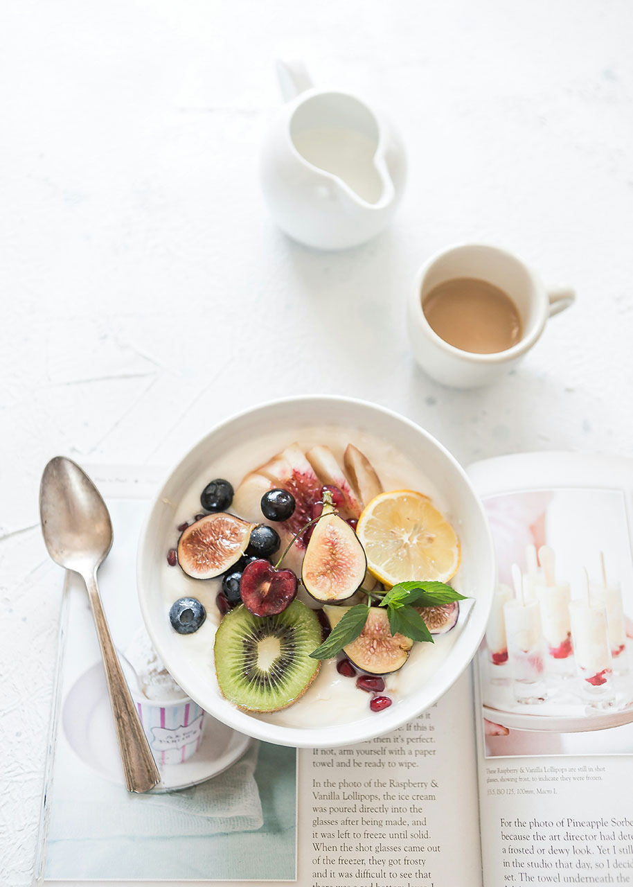 a bowl of fruit, a spoon and a cup of coffee - self-care tips