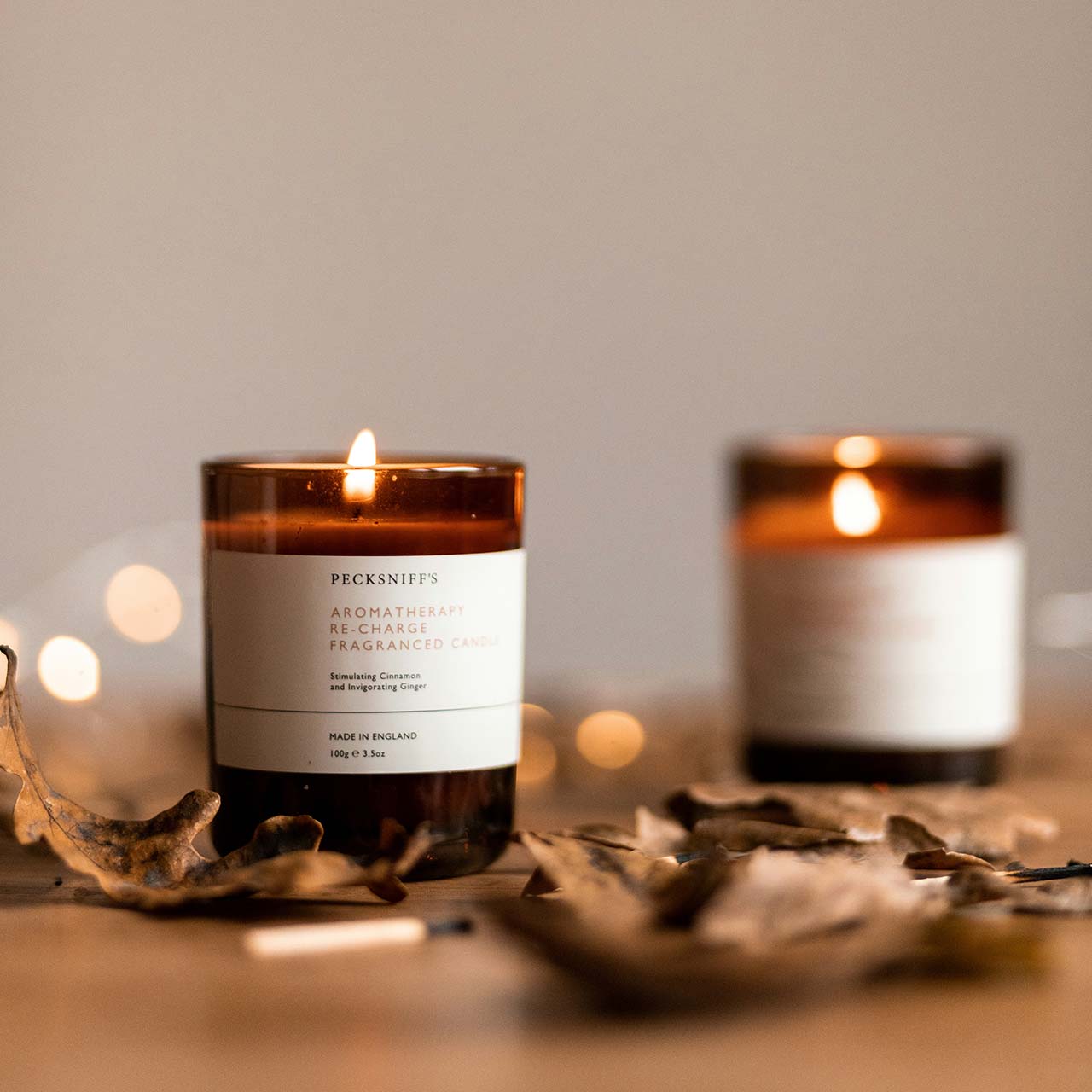 two burning candles in a glass jar with autumn leaves - cosy home