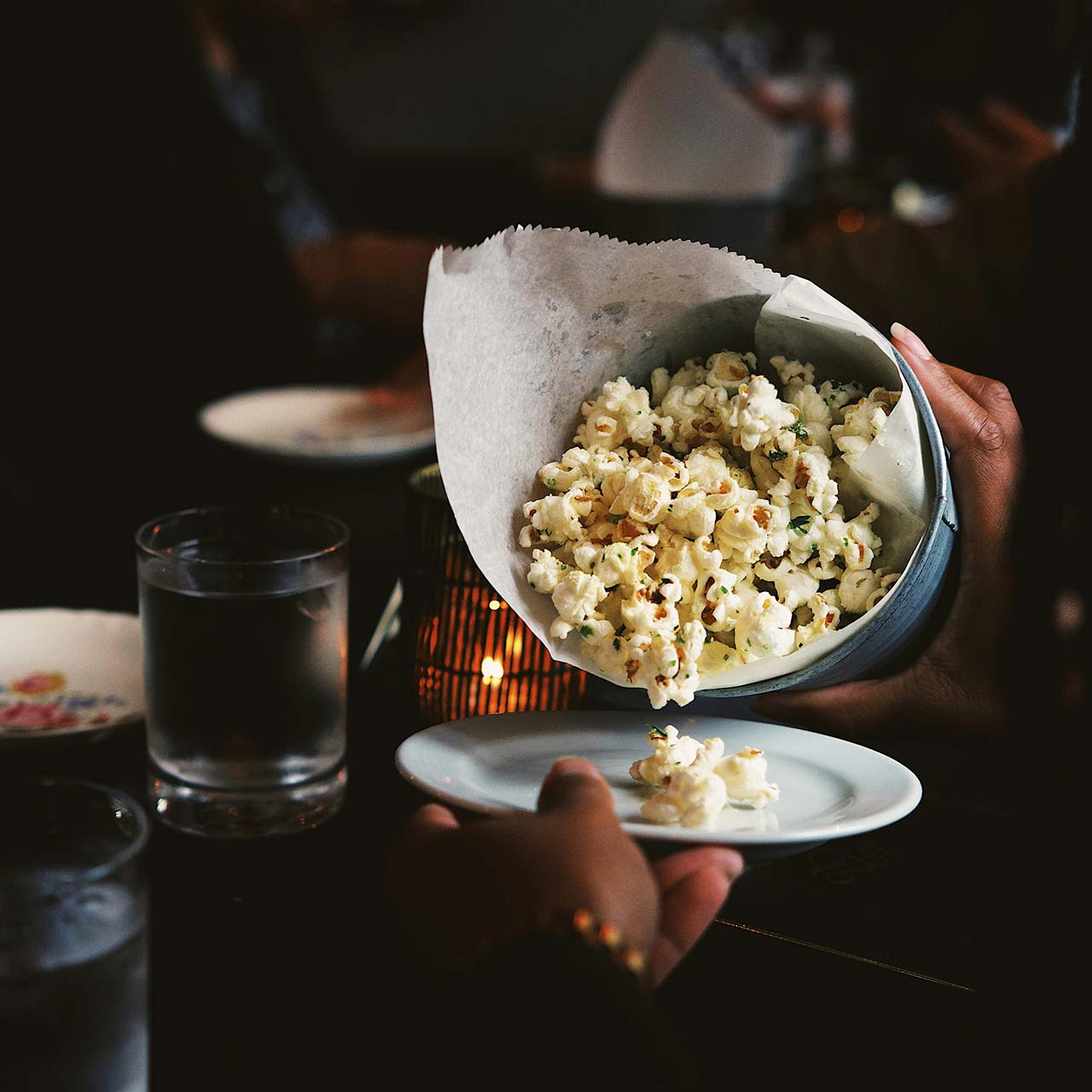 a woman putting popcorn on a plate - cosy movie night