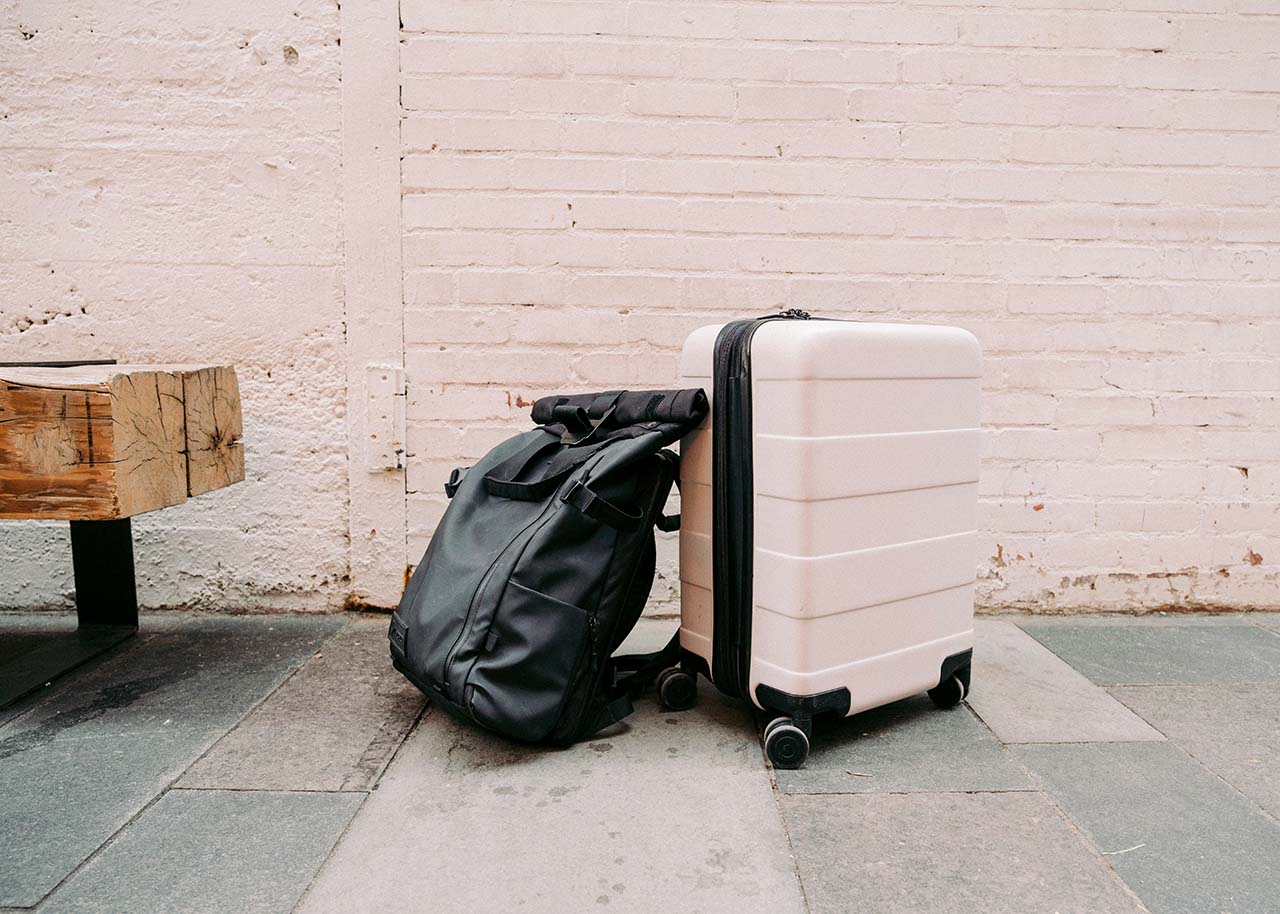 a suitcase and a backpack next to a wooden bench - travel burn out