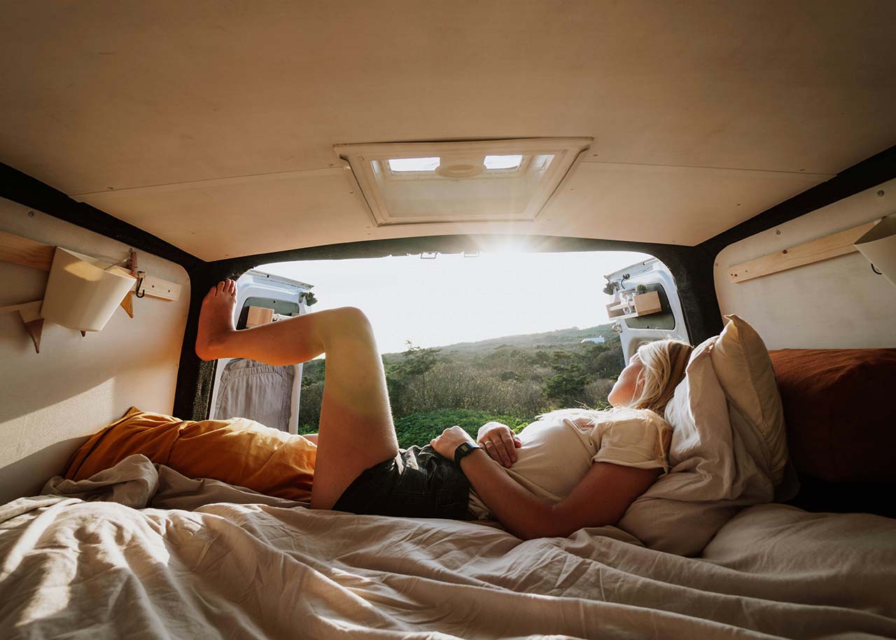 a woman on a bed with a laptop, holding a cup of coffee - next steps to future-proof your small business