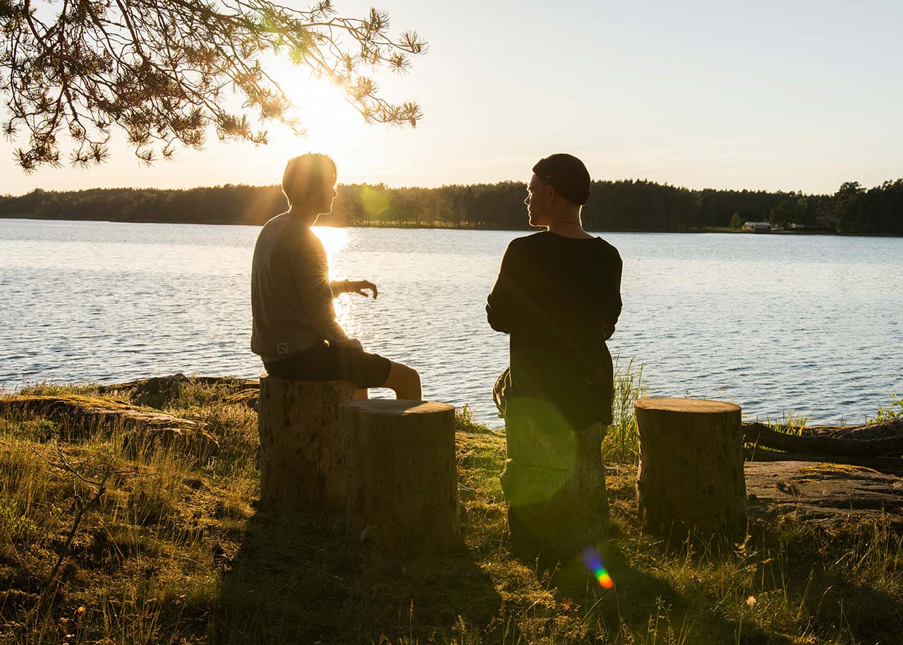 two men sitting by a lake having a conversation - authentic connections