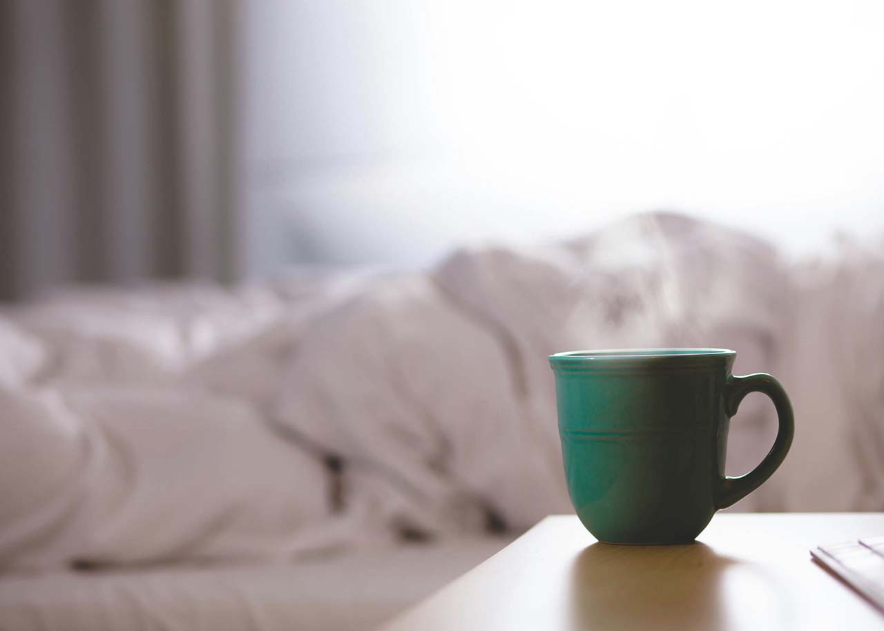 a woman on a bed with a laptop, holding a cup of coffee - next steps to future-proof your small business
